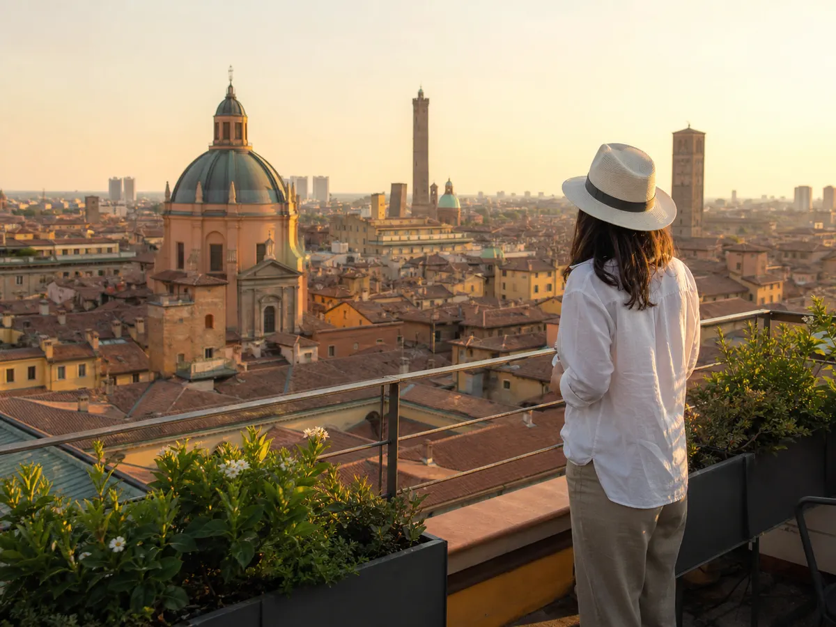 A person in a hat looking at the Bologna skyline from a balcony